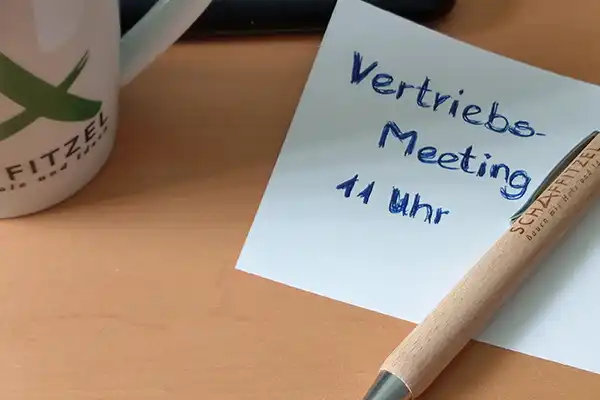 Zettel mit Aufschrift "Vertriebs-Meeting" mit Uhrzeit